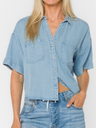 Woman wearing a light blue denim shirt and jeans on a white background